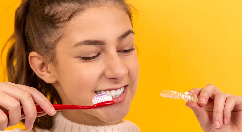 Girl Removing Invisalign Tray to Brush Her Teeth